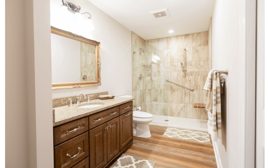 Remodeled bathroom with enough space for wheelchair accessibility, lower countertop, and walk-in shower with built-in seat and grab bars on wall.