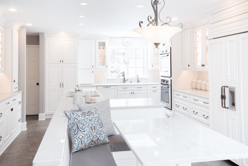 Classic white kitchen with white table, bench seating, and white cabinets.
