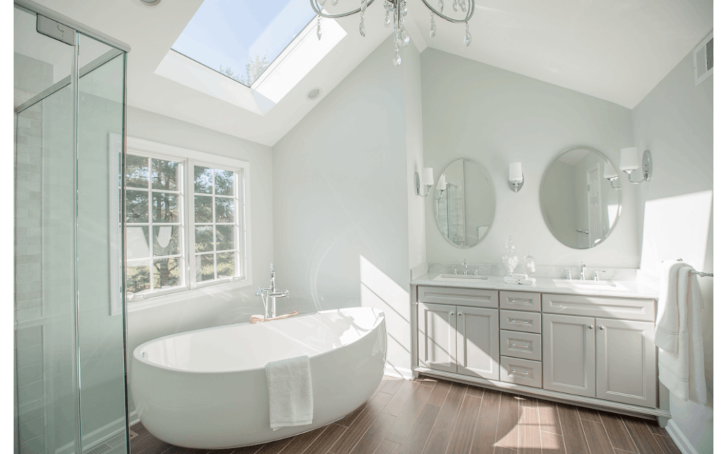 Bright vaulted master bathroom with double vanity sinks, large freestanding tub, and skylight