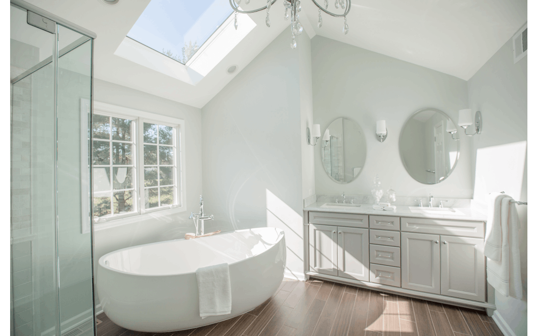 Bright vaulted master bathroom with double vanity sinks, large freestanding tub, and skylight