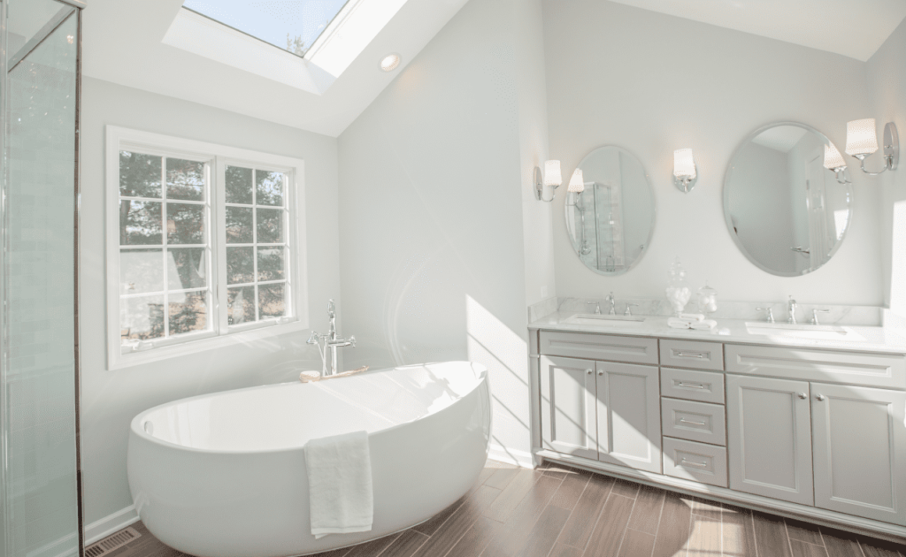 Remodeled primary bathroom with skylight, large soaking tub, and double sink vanity