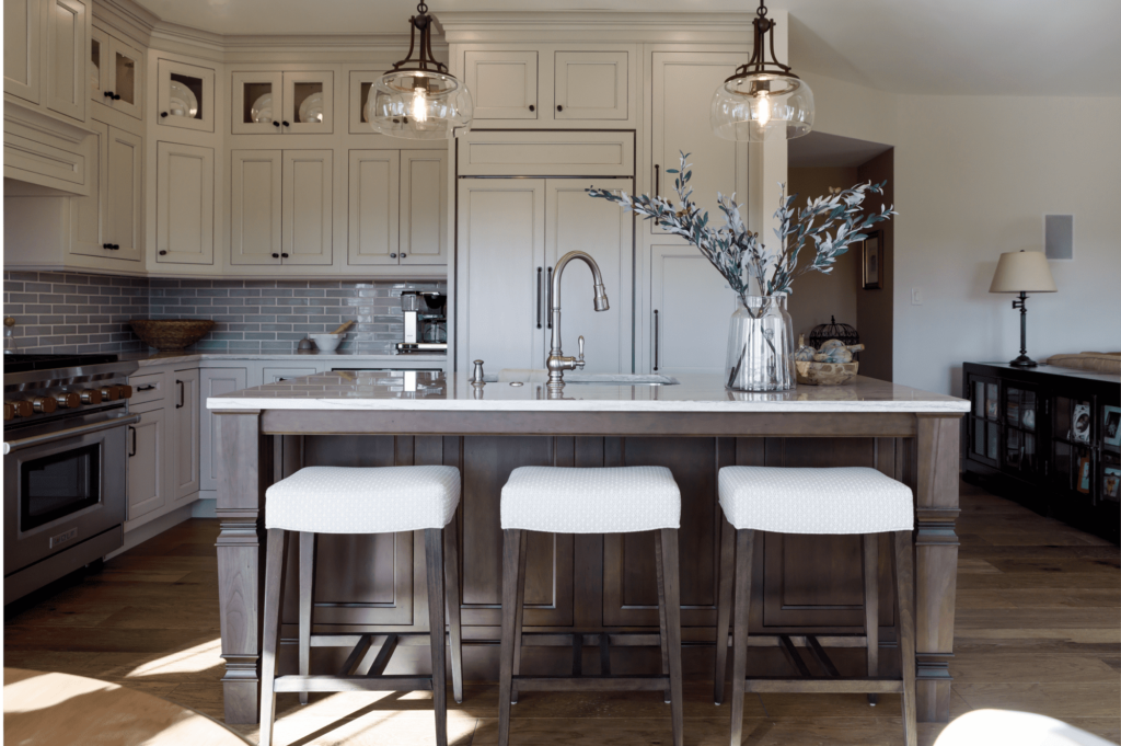kitchen remodel with island, white cabinets, gray subway tile backsplash, and wood floors.