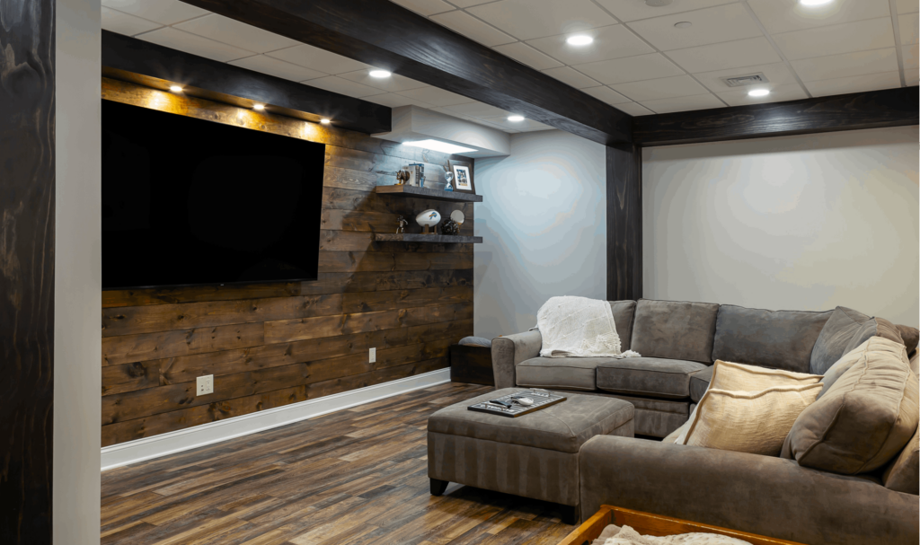 Basement remodel with recessed lighting, dark wood floors, and couches facing TV