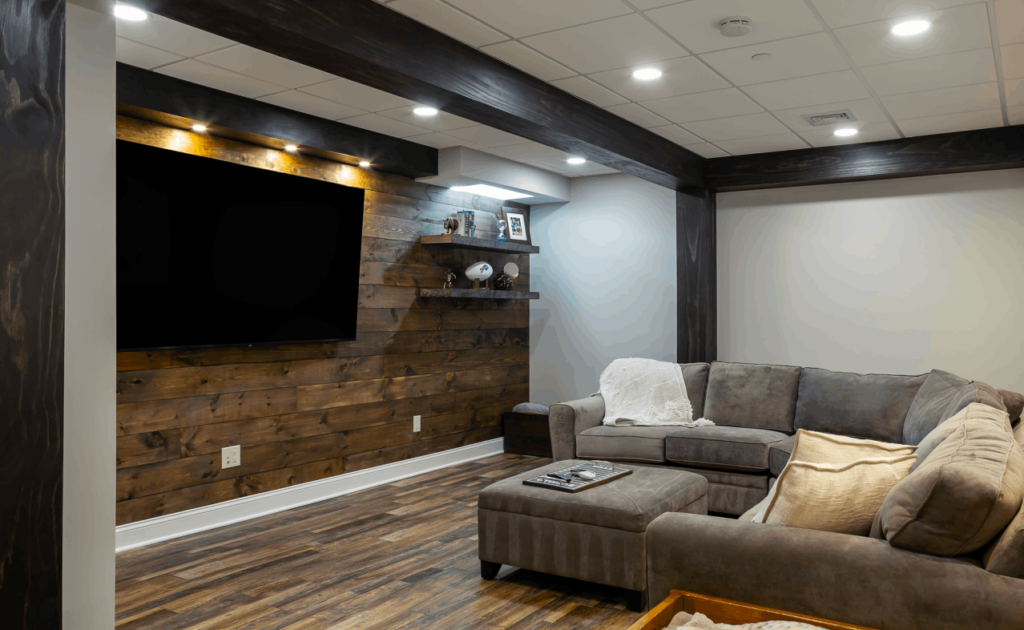 Remodeled basement with recessed lighting, hanging TV, and sectional sofa.