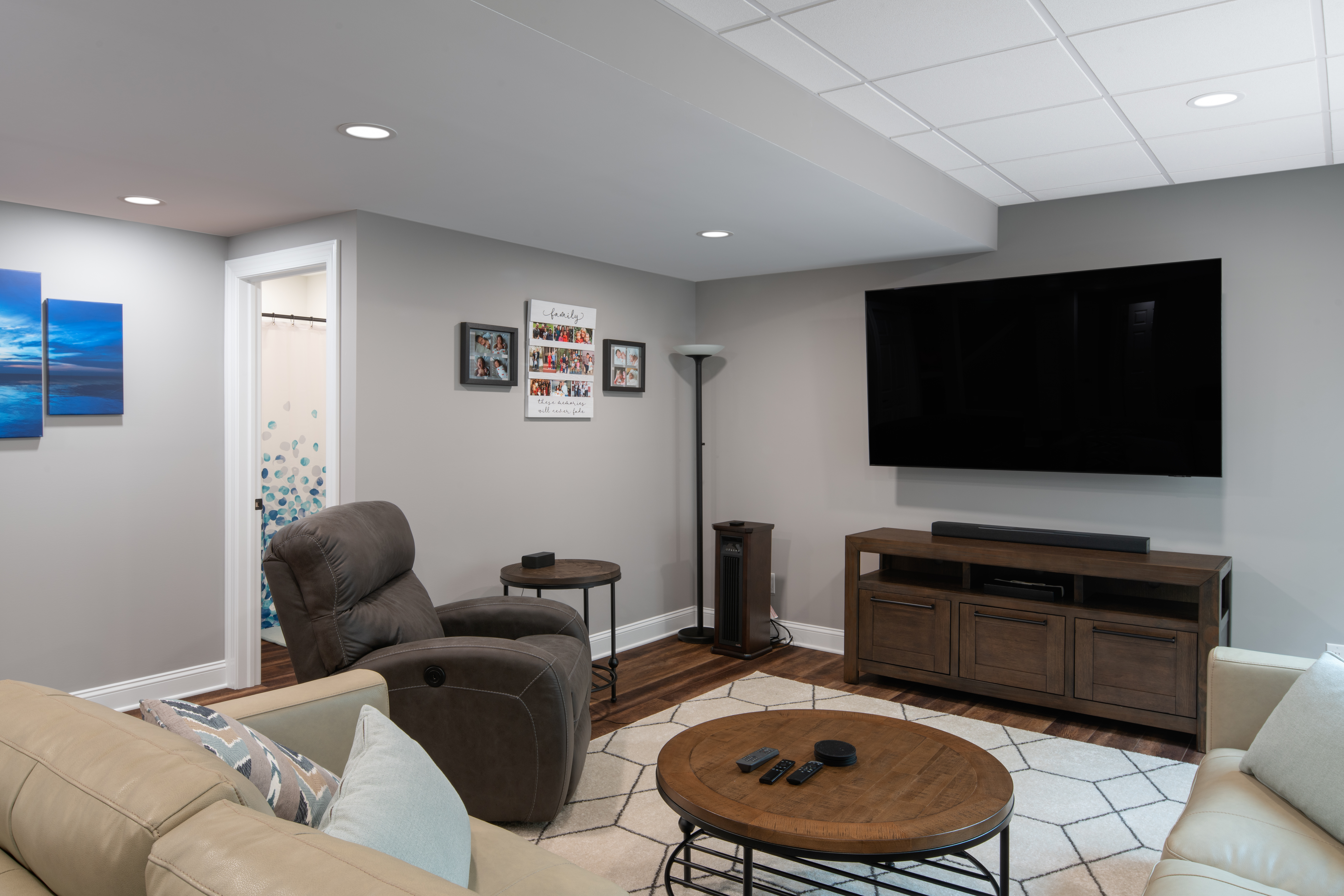 Cozy and bright basement entertainment space with partial drywall and partial tiled ceiling