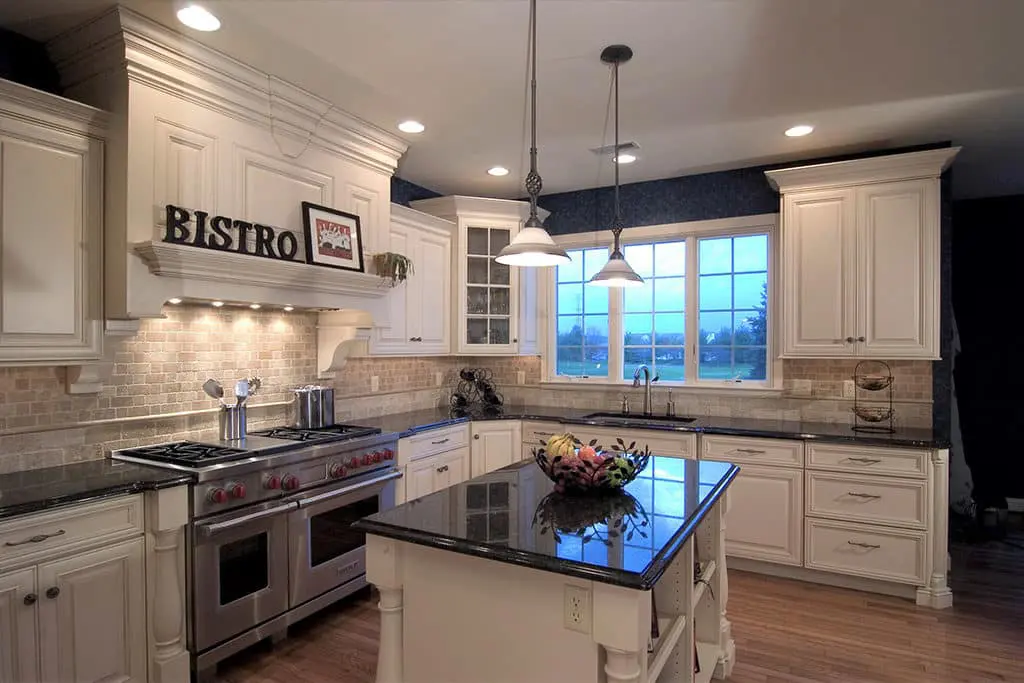 Modern kitchen remodel with small island, pendant lights, and a 'bistro' sign on the hood.