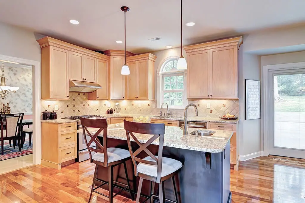 Warm wood kitchen remodel with grey marble countertops and an island.