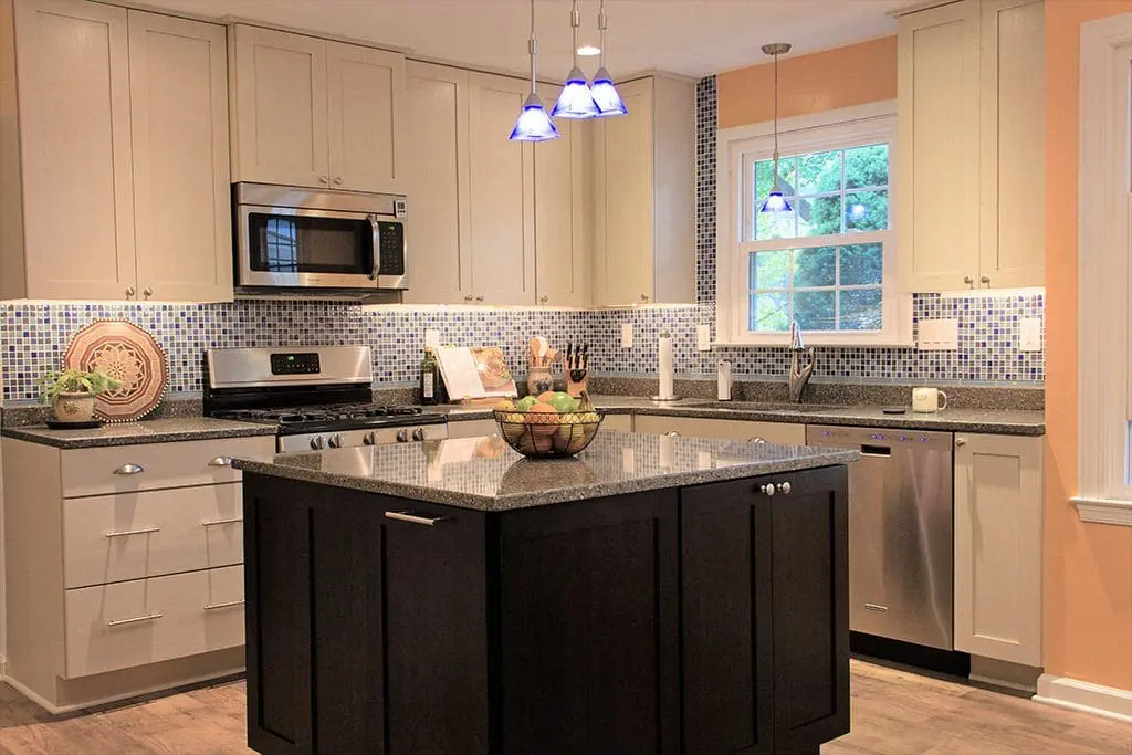 Black and white kitchen with grey marle countertops and blue tiled backsplash.