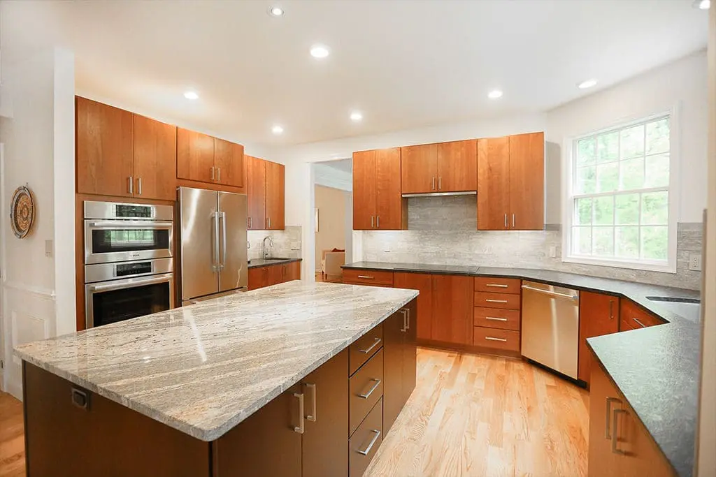 Modern kitchen remodel with brown cabinets and silver handle and appliances.
