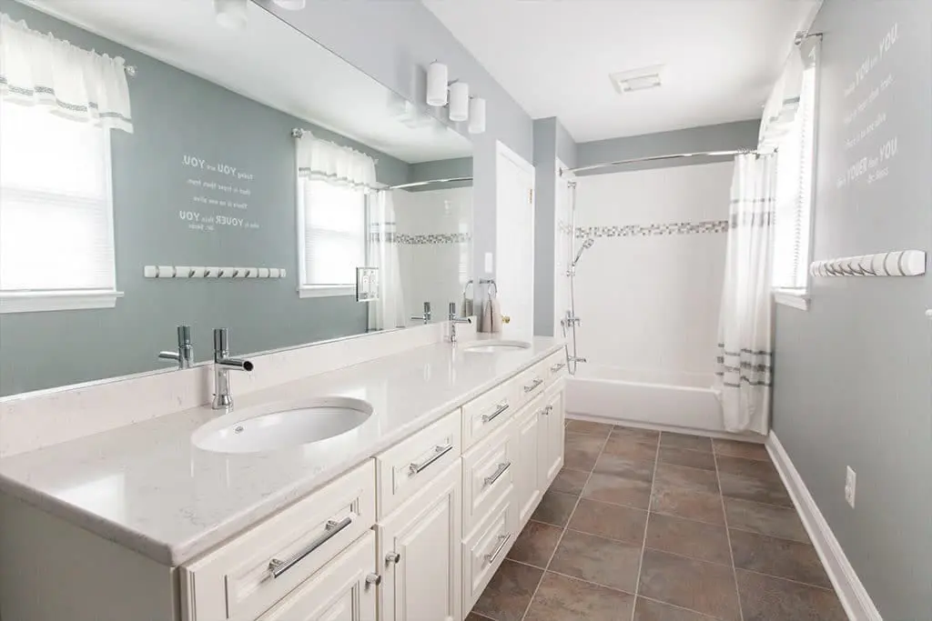 White and gray bathroom remodel with his and hers sinks and a large mirror.