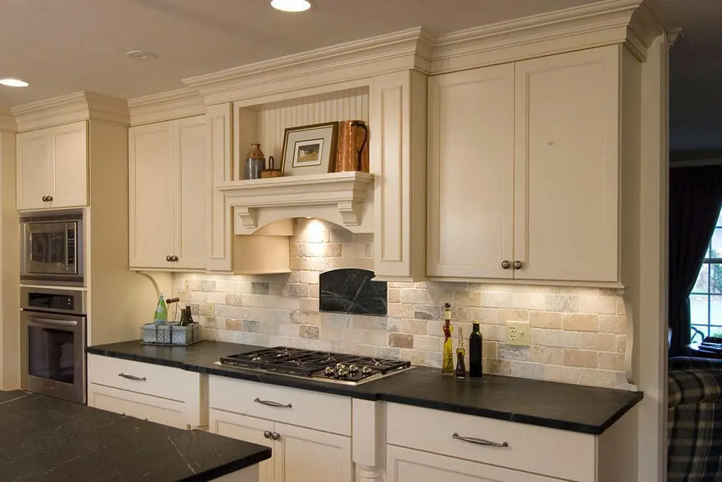 White Kitchen remodel with black marble countertops and stone backsplash.