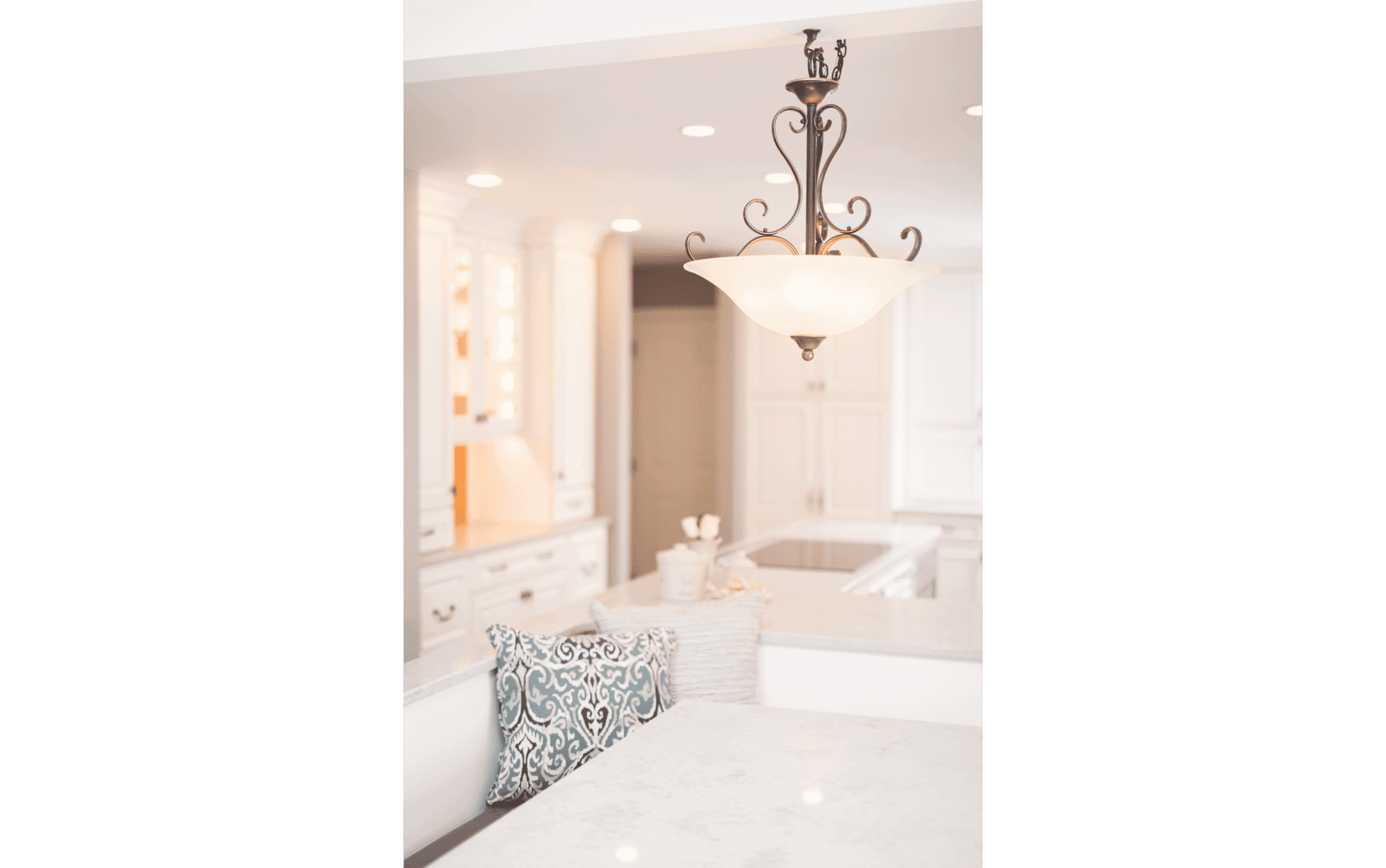 Closeup of classic white kitchen renovation with detailed traditional pendant light and custom dining area booth seating