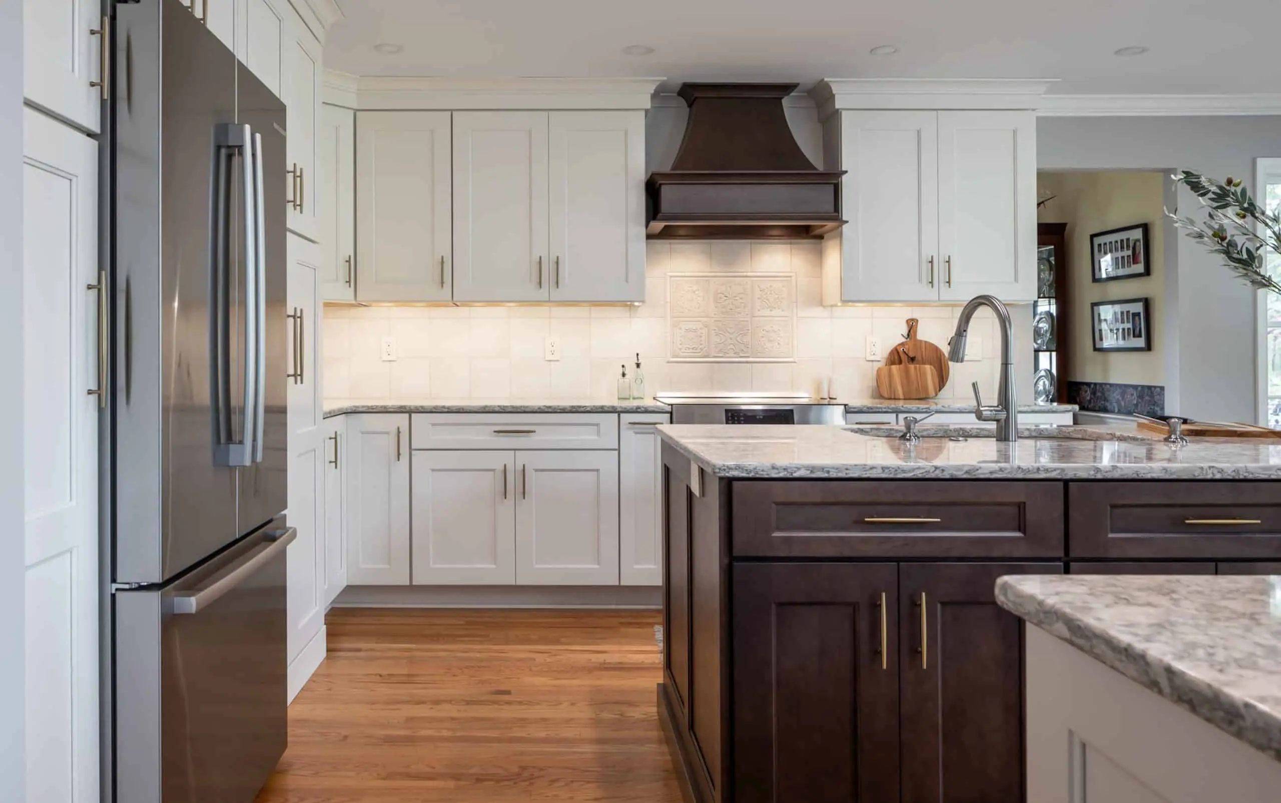 Updated grey kitchen cabinetry with contrasting dark wooden island and custom range hood
