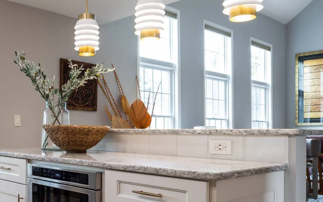 Two-tiered island with funky modern pendants overhead and natural light from floor-to-ceiling windows