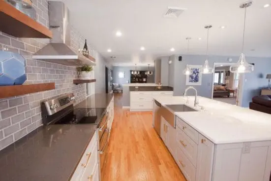 Renovated kitchen with wood floors, gray subway tile backsplash, and large white island.