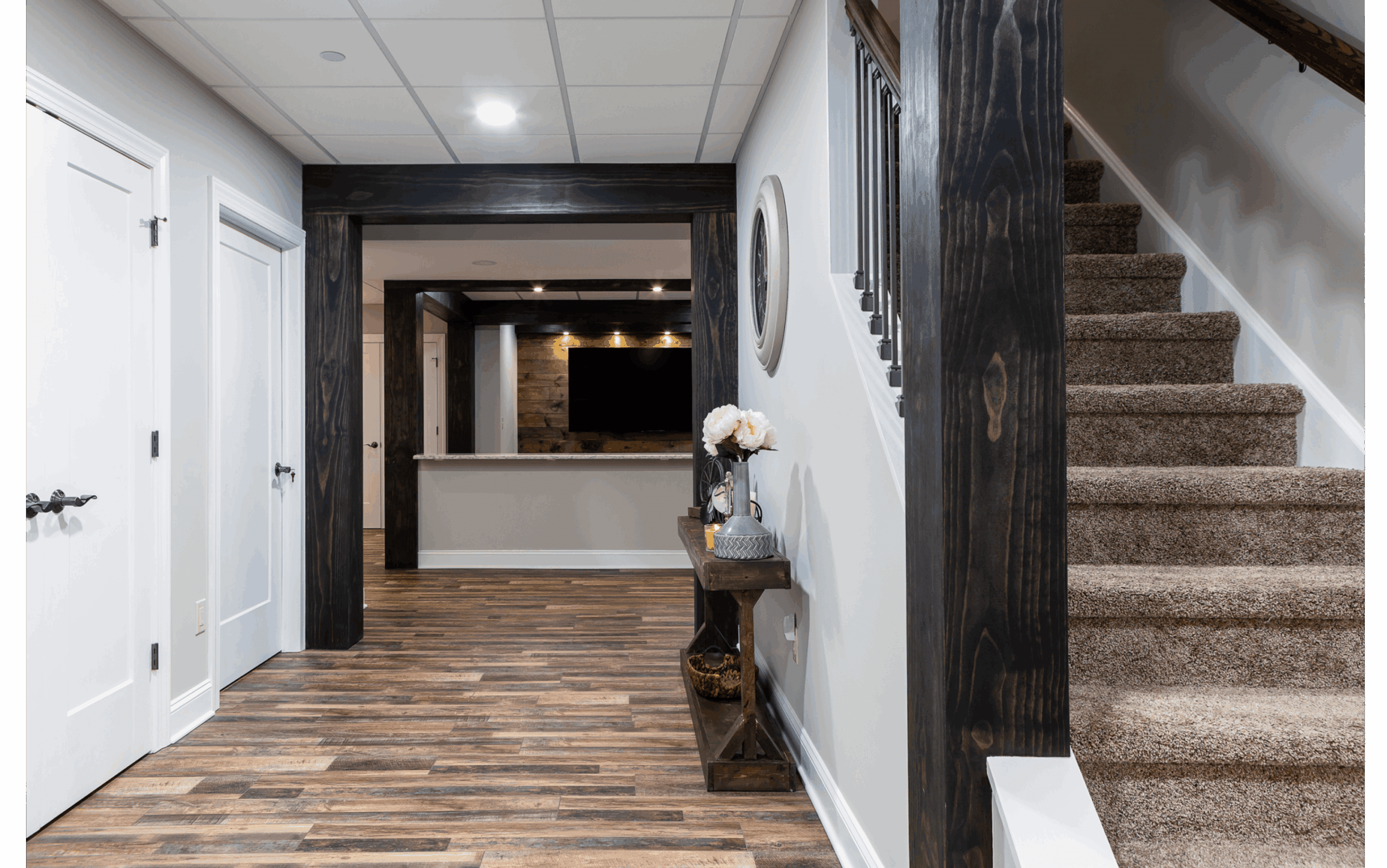 rustic basement hallway with dark wooden beams and contrasting dark hardwood floors