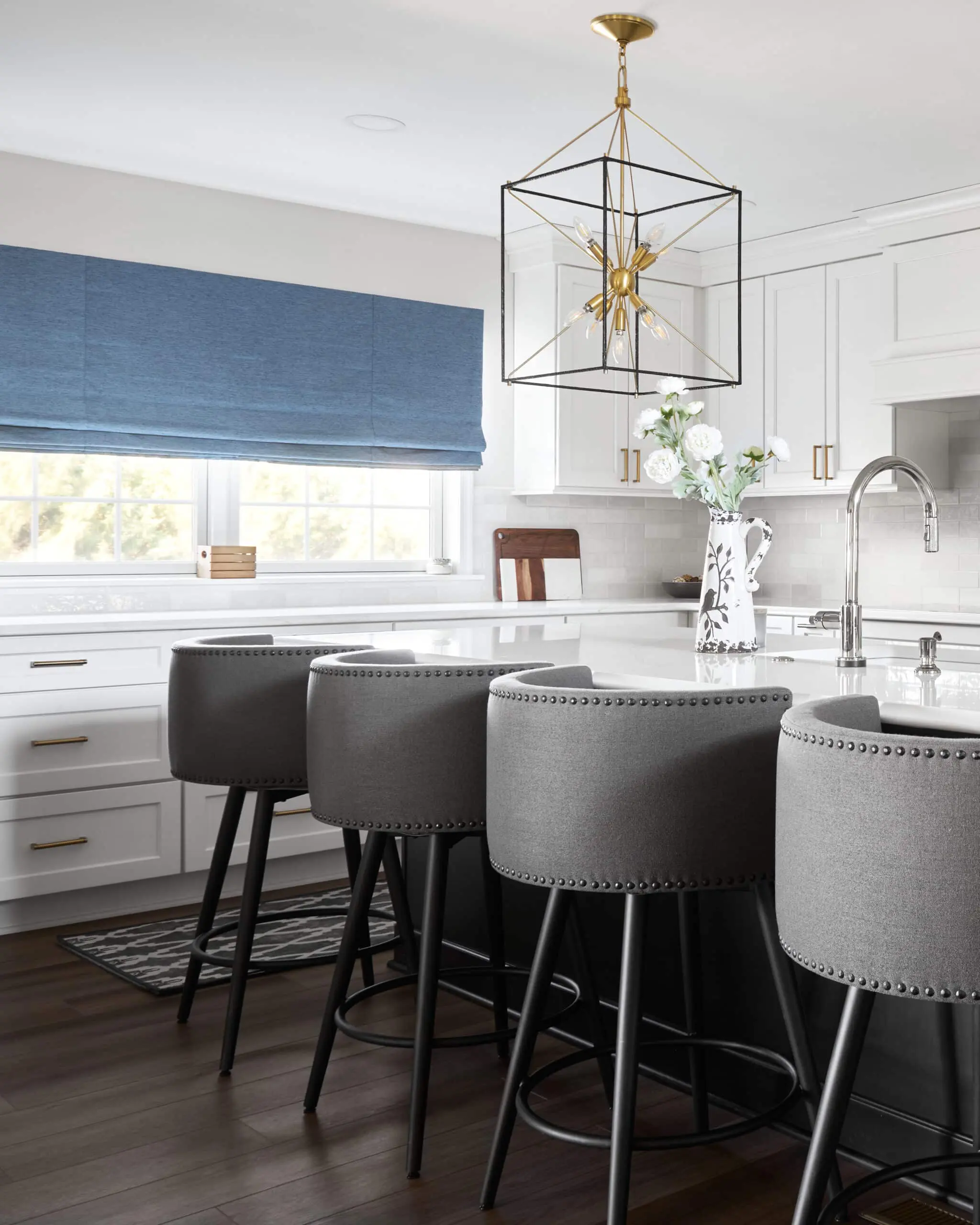 A custom remodeled kitchen with white textured tile backsplash, white cabinets, and white granite countertops.