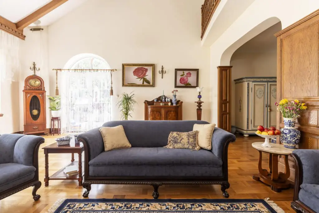 Cobalt blue sofa and other antique furniture on a wooden floor in a spacious living room interior of a federal style home