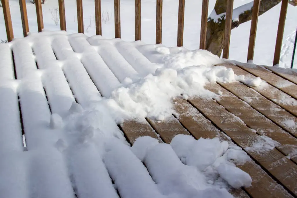 Partially shoveled snow on a wooden deck