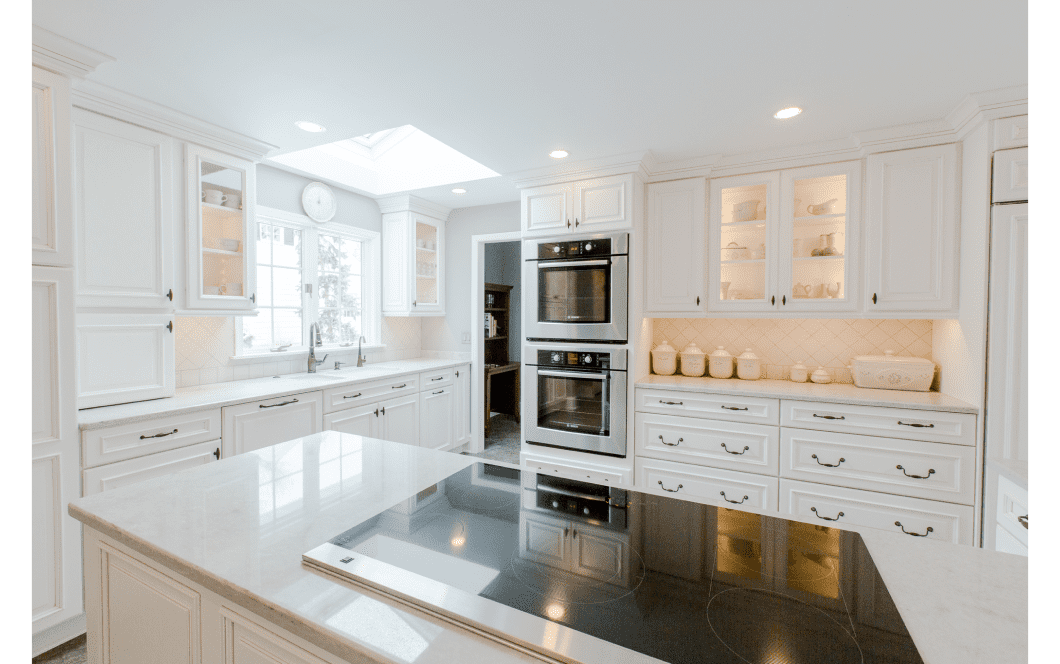 Bright white kitchen with skylight over the sink and a large island with built-in stovetop