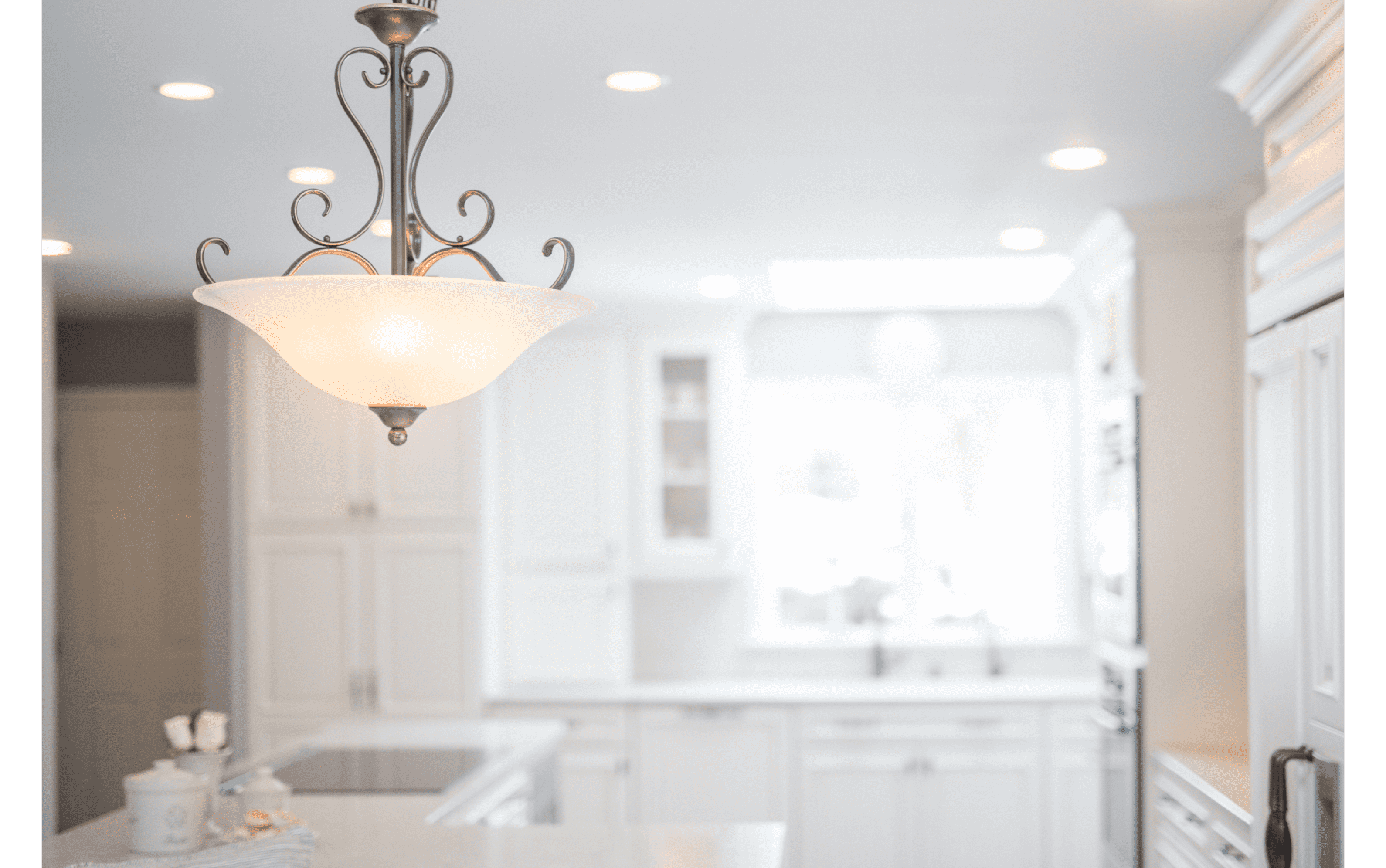 Closeup of detailed traditional pendant light in front of classic white kitchen remodel