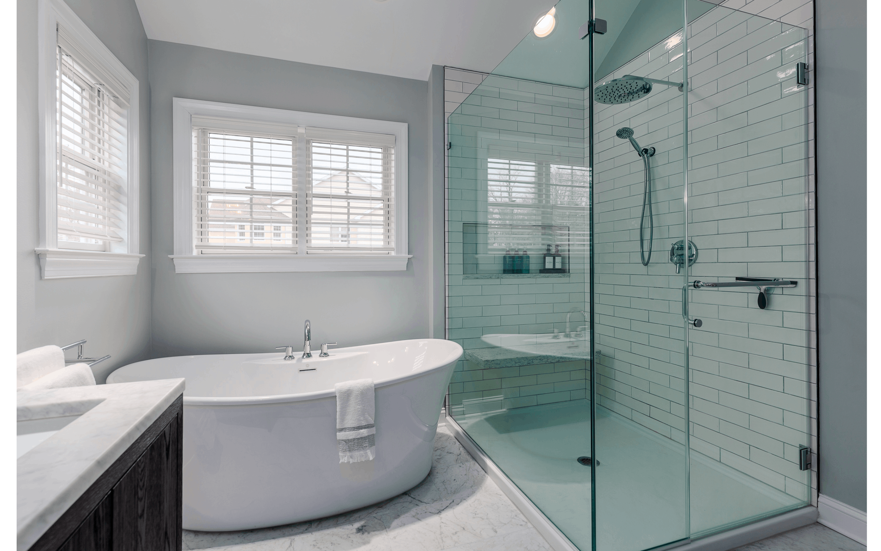 Neutral grey bathroom upgrade with large soaking tub, glass shower, and multiple windows letting in ample natural light