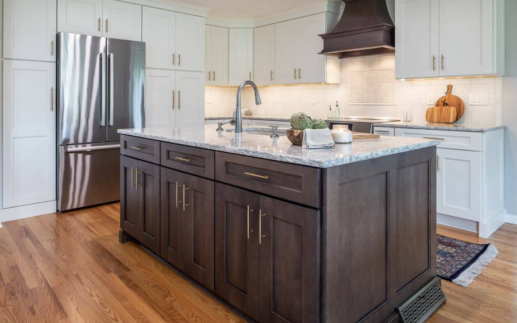 Updated grey kitchen cabinetry with contrasting dark wooden island and custom range hood