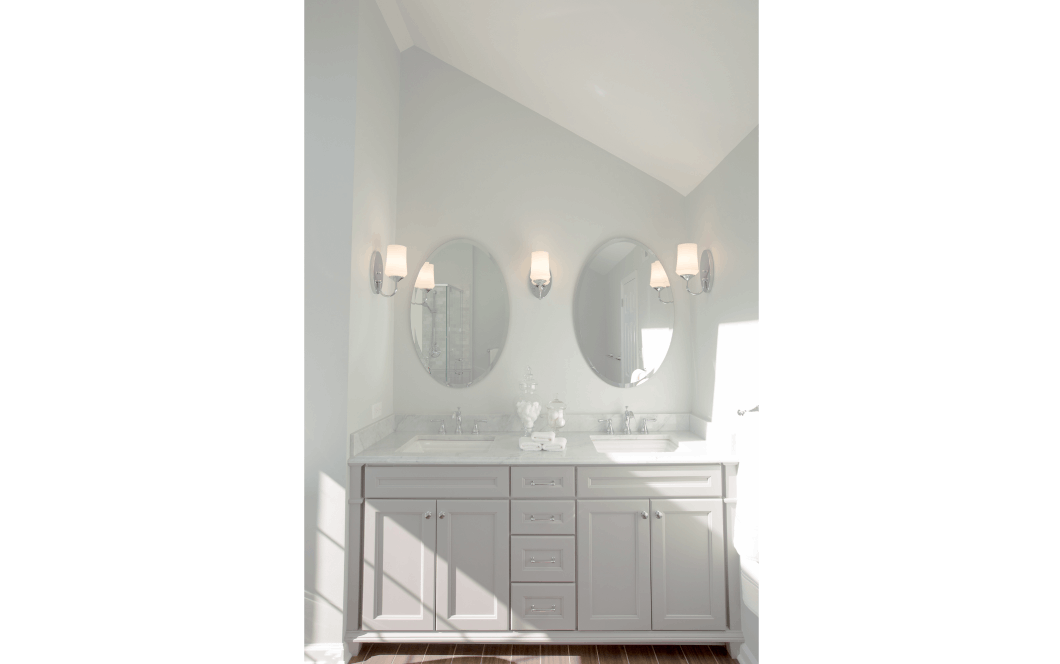 white countertops and vanity with circle mirrors and wall sconces