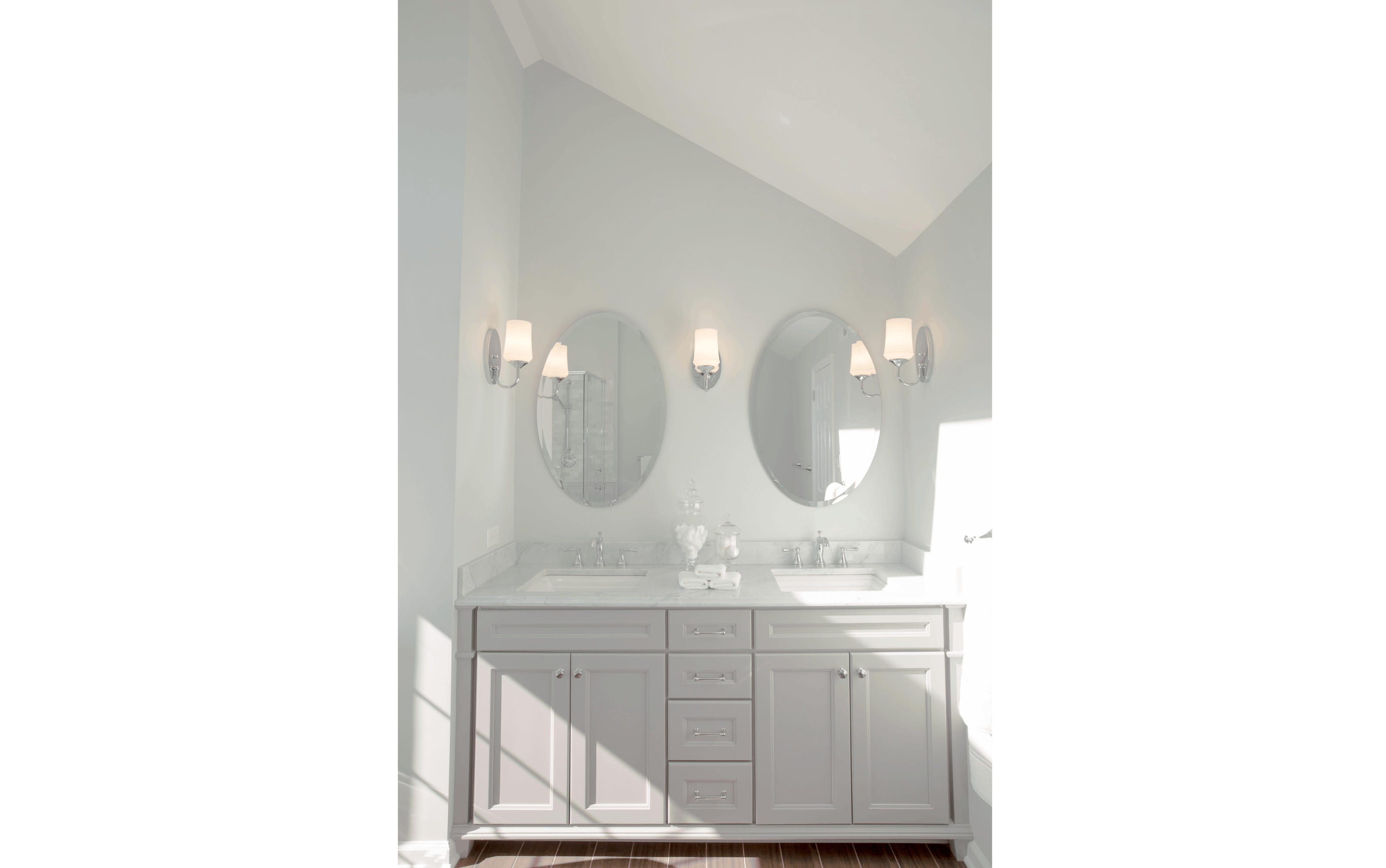 Simple grey double-sink bathroom vanity sitting against half-vaulted bathroom niche