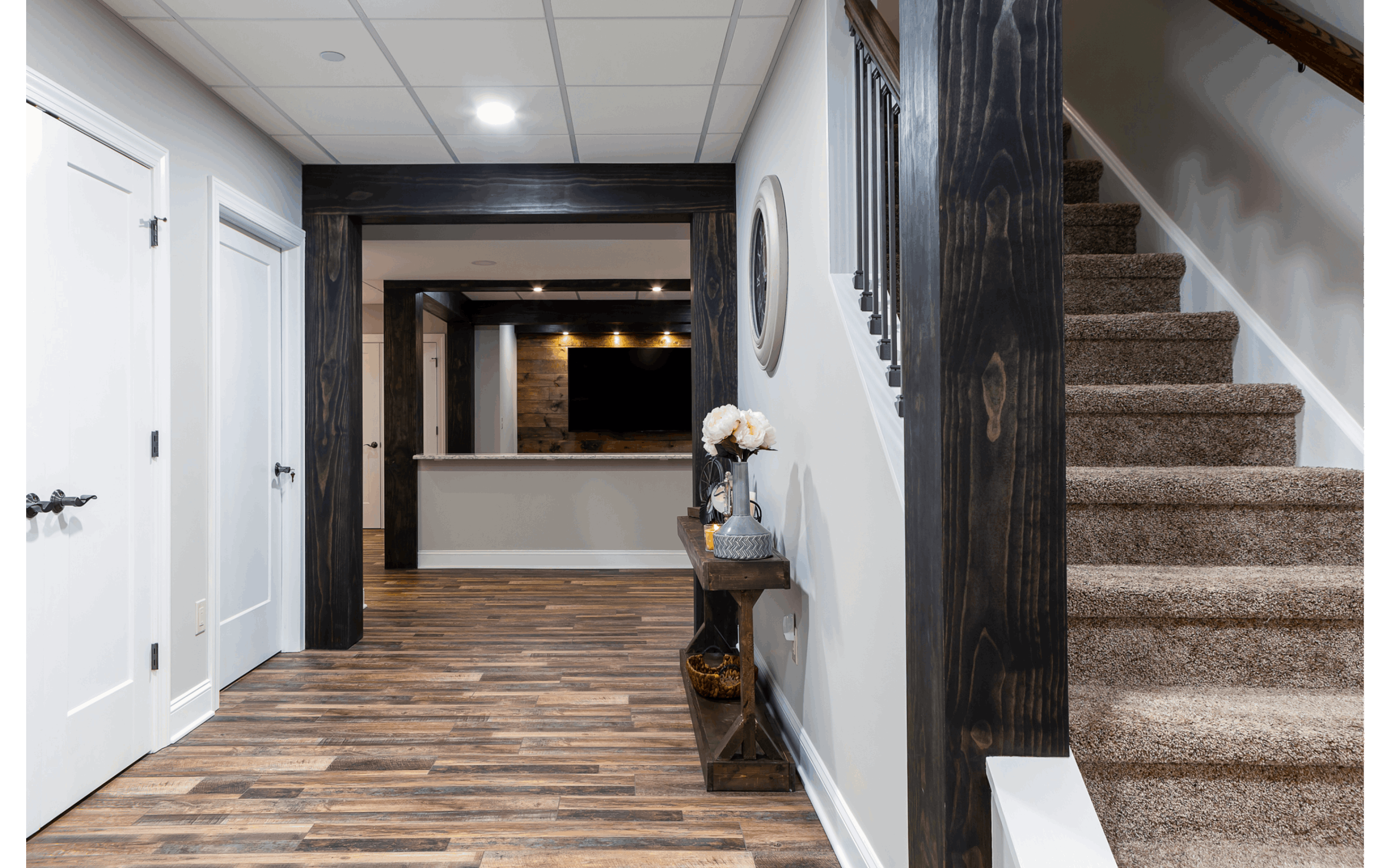 rustic basement hallway with dark wooden beams and contrasting dark hardwood floors
