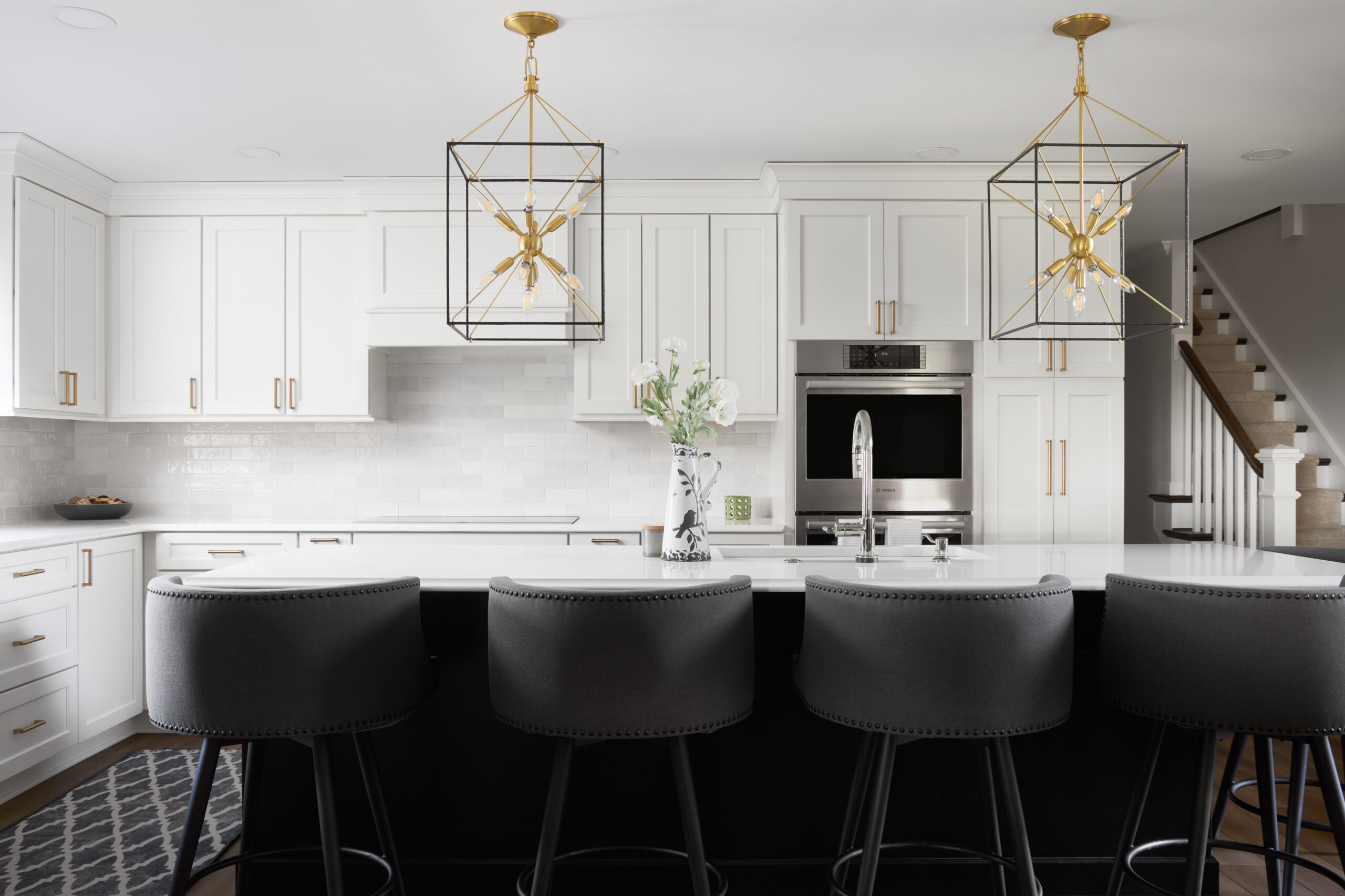 A custom remodeled kitchen with white textured tile backsplash, white cabinets, and white granite countertops.